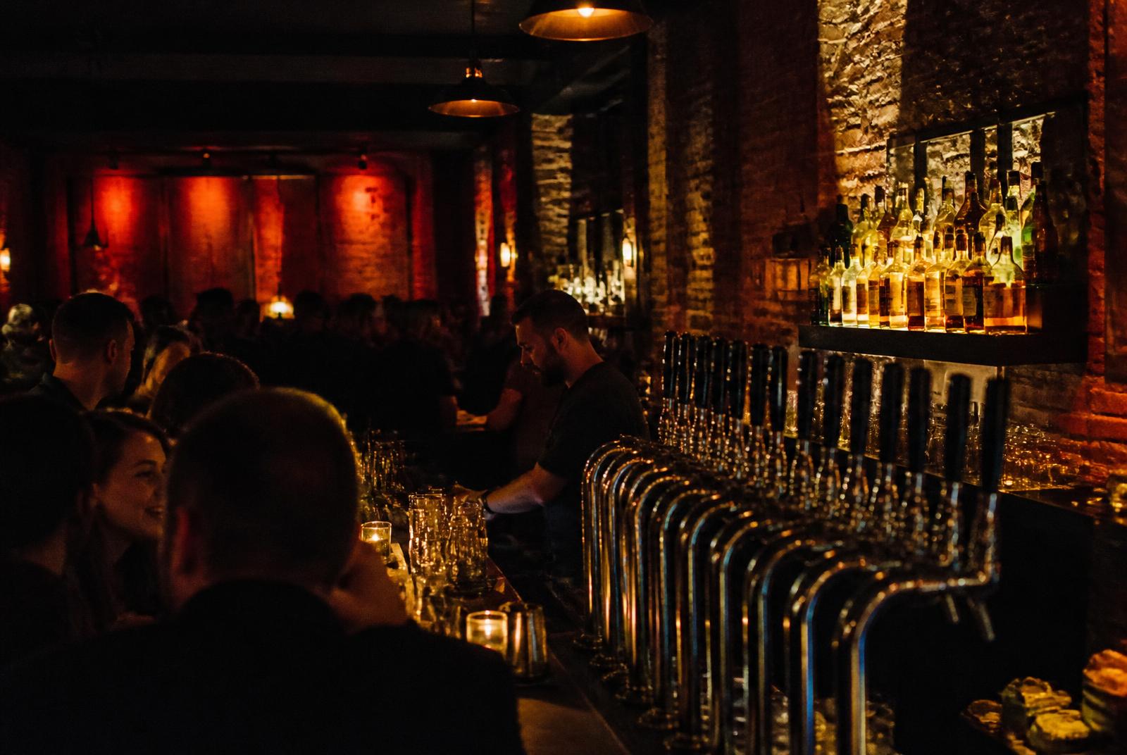Row of taps along a dark, red-lit bar